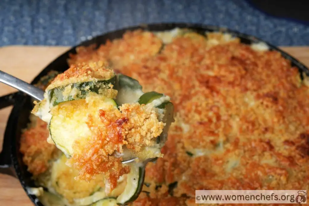 A spoonful lifted in the air of a zucchini gratin