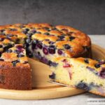 An Ina Garten blueberry ricotta cake being served on a wooden board