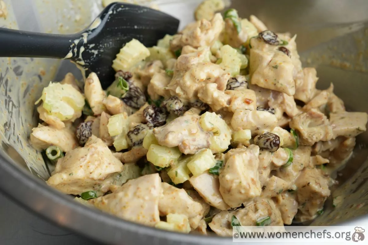 Mixing chicken curry salad ingredients together 