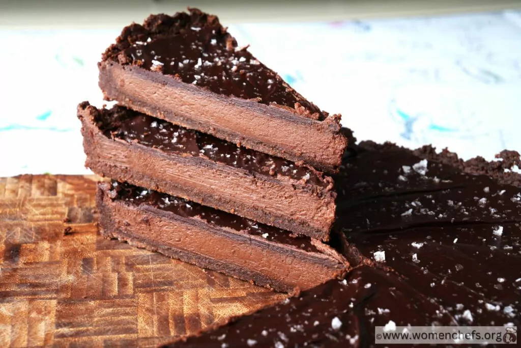 slices of chocolate tart stacked on top of each other on a wooden board