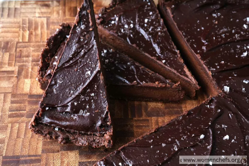 slices of dark chocolate tarts on top of a wooden board