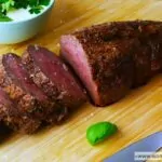 Perfectly cooked Ina Garten filet of beef sliced on a wooden board